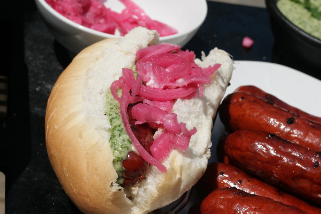 Choripan - Chorizo topped with pickled onions and chimmichurri sauce