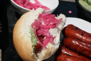 Choripan - Chorizo topped with pickled onions and chimmichurri sauce